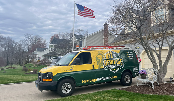 A Heritage Heating and Air service van in front of the grey house