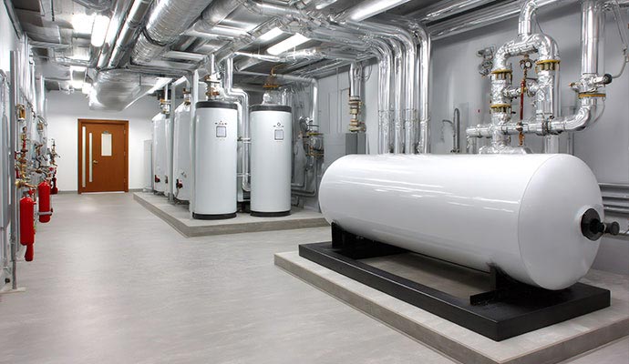 A large commercial boiler room featuring large water heater tanks