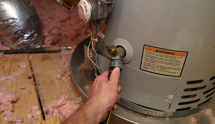 A professional connecting a hose to a water heater drain valve