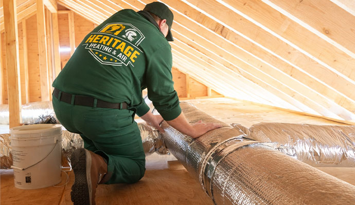A technician of Heritage Heating and Air inspecting ductwork