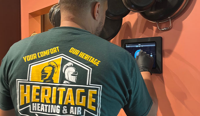 A technician of Heritage Heating and Air inspecting thermostat
