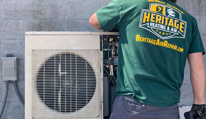 A technician repairing an outdoor heat pump unit