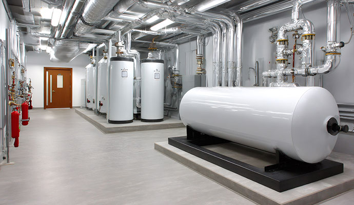 A wide shot of a sterile commercial mechanical room featuring a large horizontal white thermal storage tank