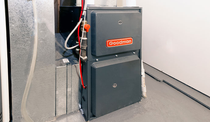 Dark grey Goodman gas furnace installed in a basement