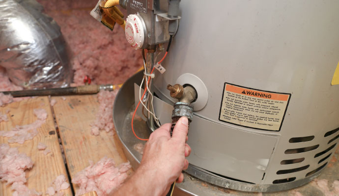 Hand attaching hose to water heater drain valve