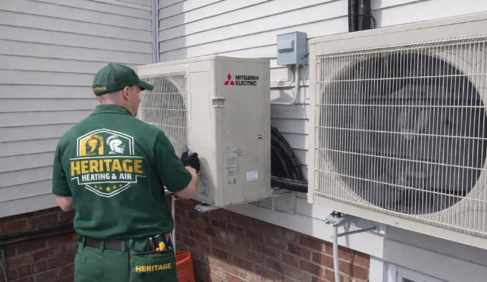 Heritage Heating and Air technician inspecting outdoor unit