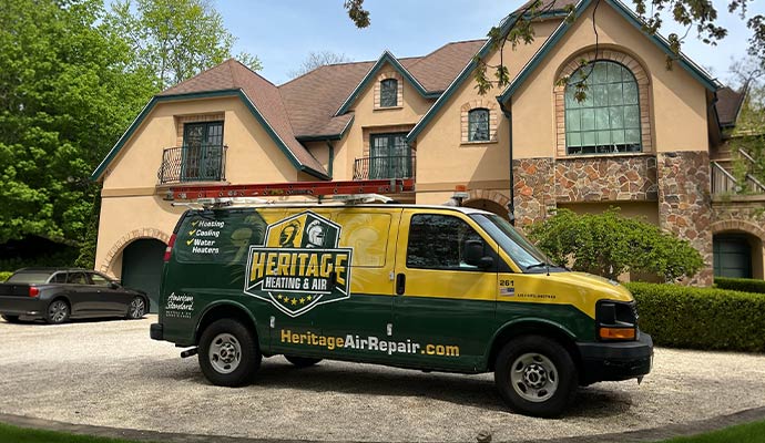 Heritage Heating and Air service van parked in front of a large residential house