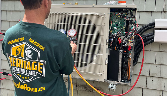 Heritage Heating and Air technician checking outdoor AC unit