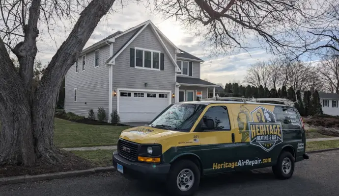 Heritage Heating & Air service van parked in front of a residential home.