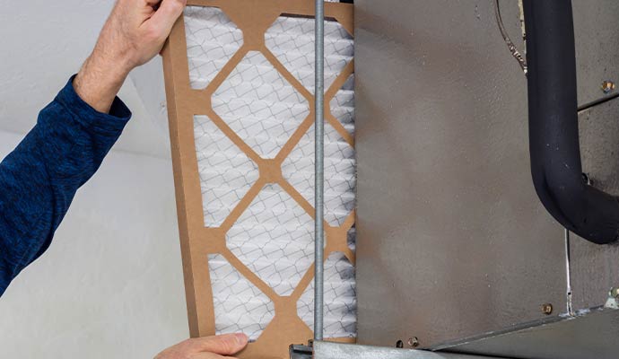 Technician replacing a clean HVAC air filter in an air handler unit