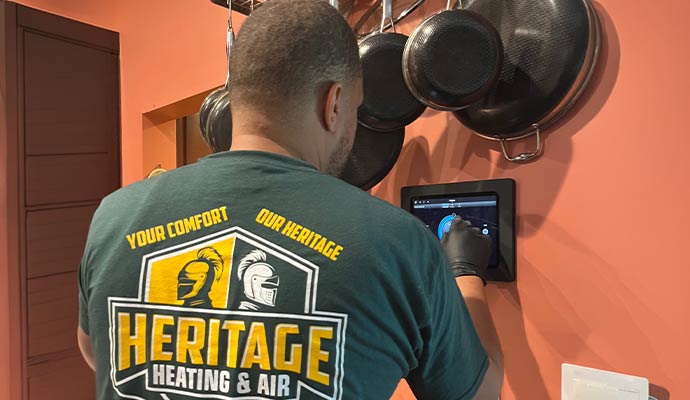HVAC professional from Heritage Heating and Air configuring a wall-mounted smart home control panel