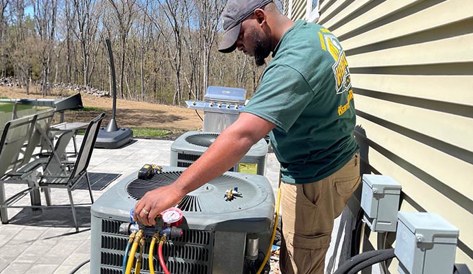 HVAC technician checking pressure gauges on an outdoor air conditioning unit
