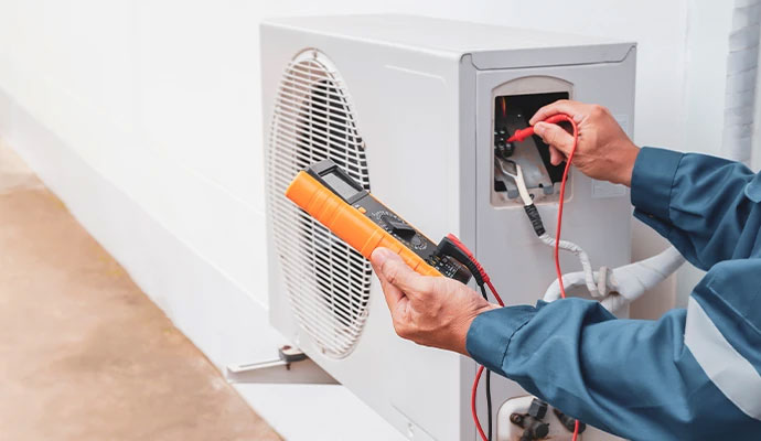 Technician using multimeter to test electrical connections air conditioning unit