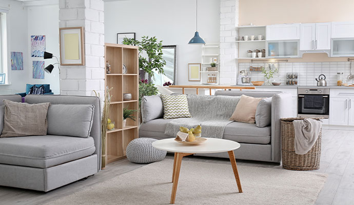 A modern open-concept living room and kitchen area featuring white brick pillars and grey sofas