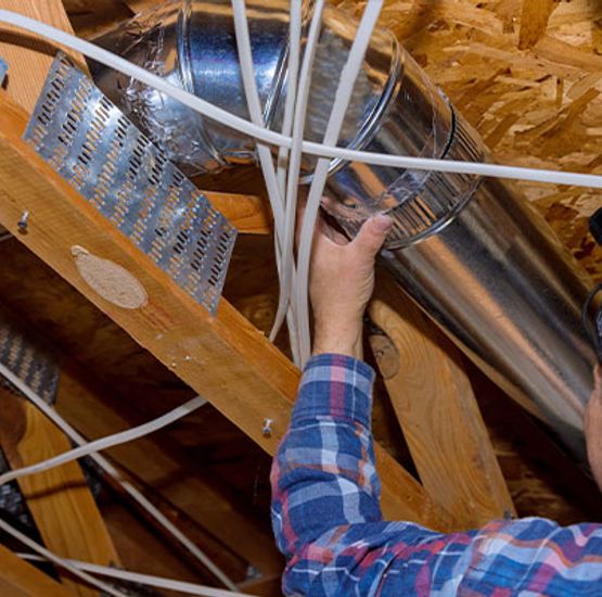 Technician installing rigid metal ducting in attic