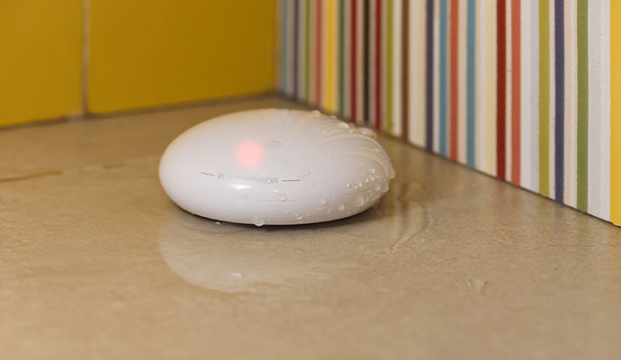 A pebble-shaped white smart flood sensor