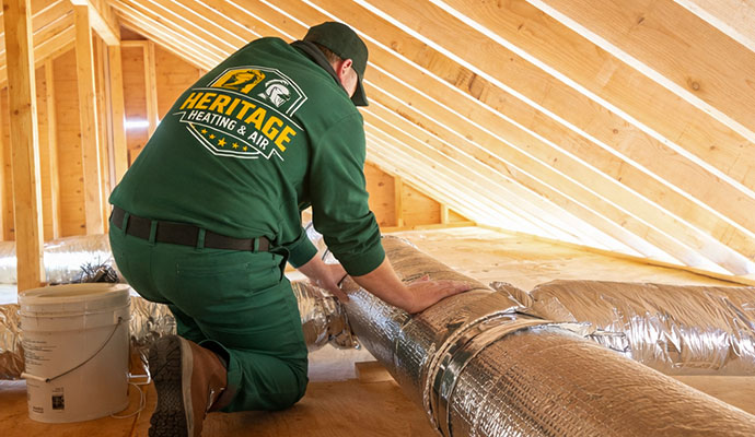 A technician is installing duct system in an attic