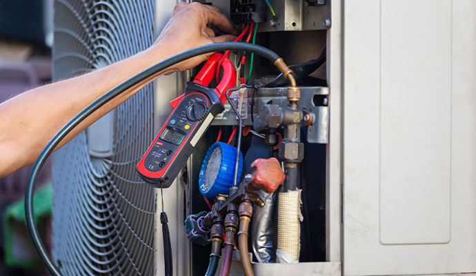 Technician diagnosing air conditioner with multimeter and gauges